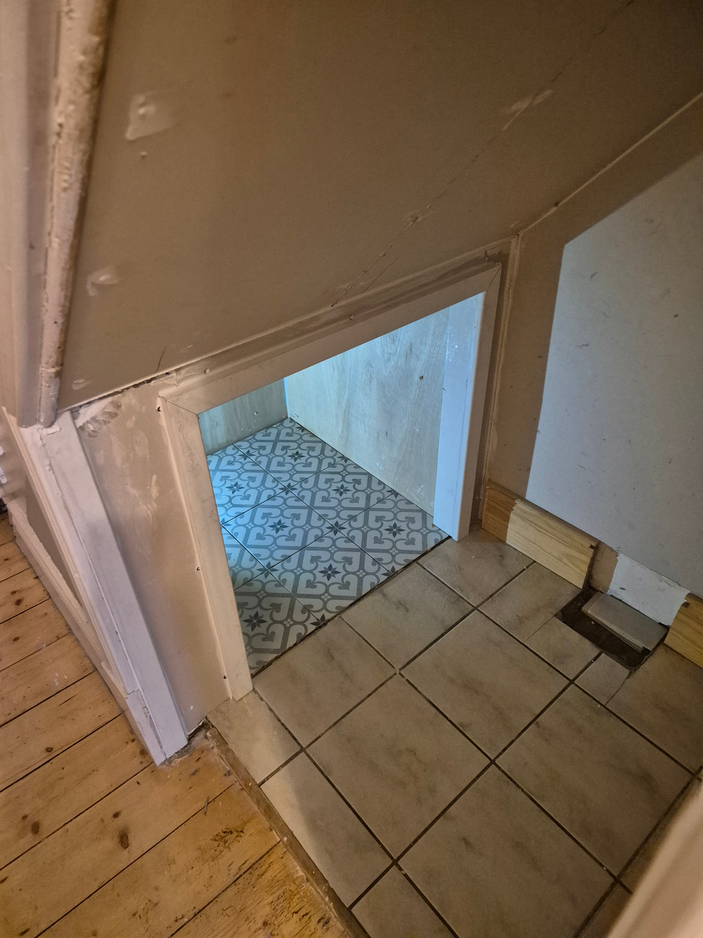 Custom under-stairs cat snug with patterned tiled floor and plywood walls