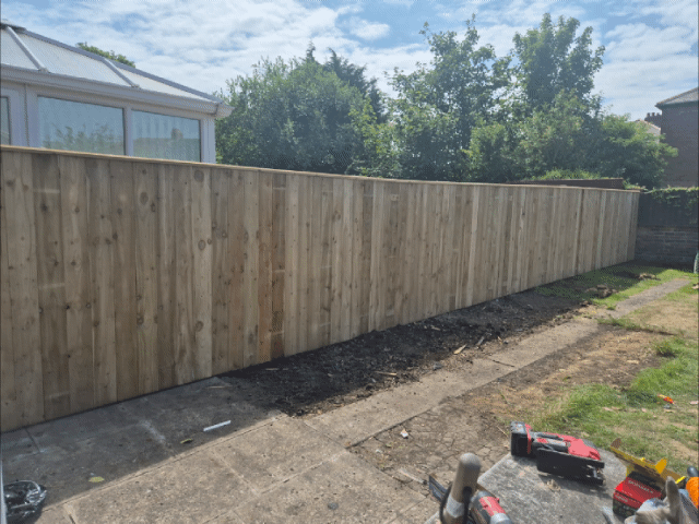 Newly built 20 meter timber fence along a garden boundary with brick wall base